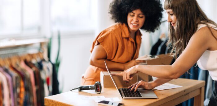 Two women looking at a laptop at a retail business