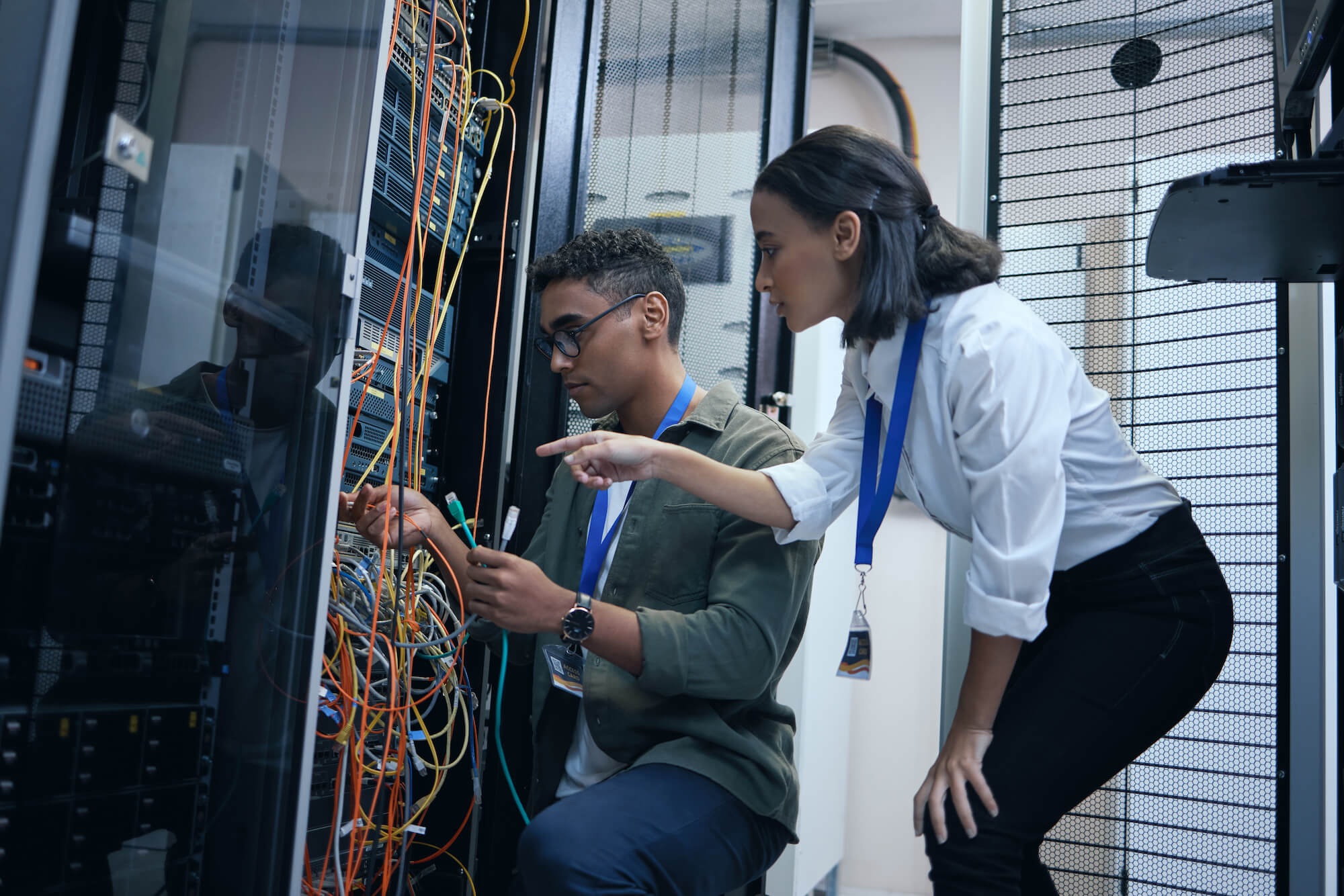 Two IT technicians maintaining a server rack.