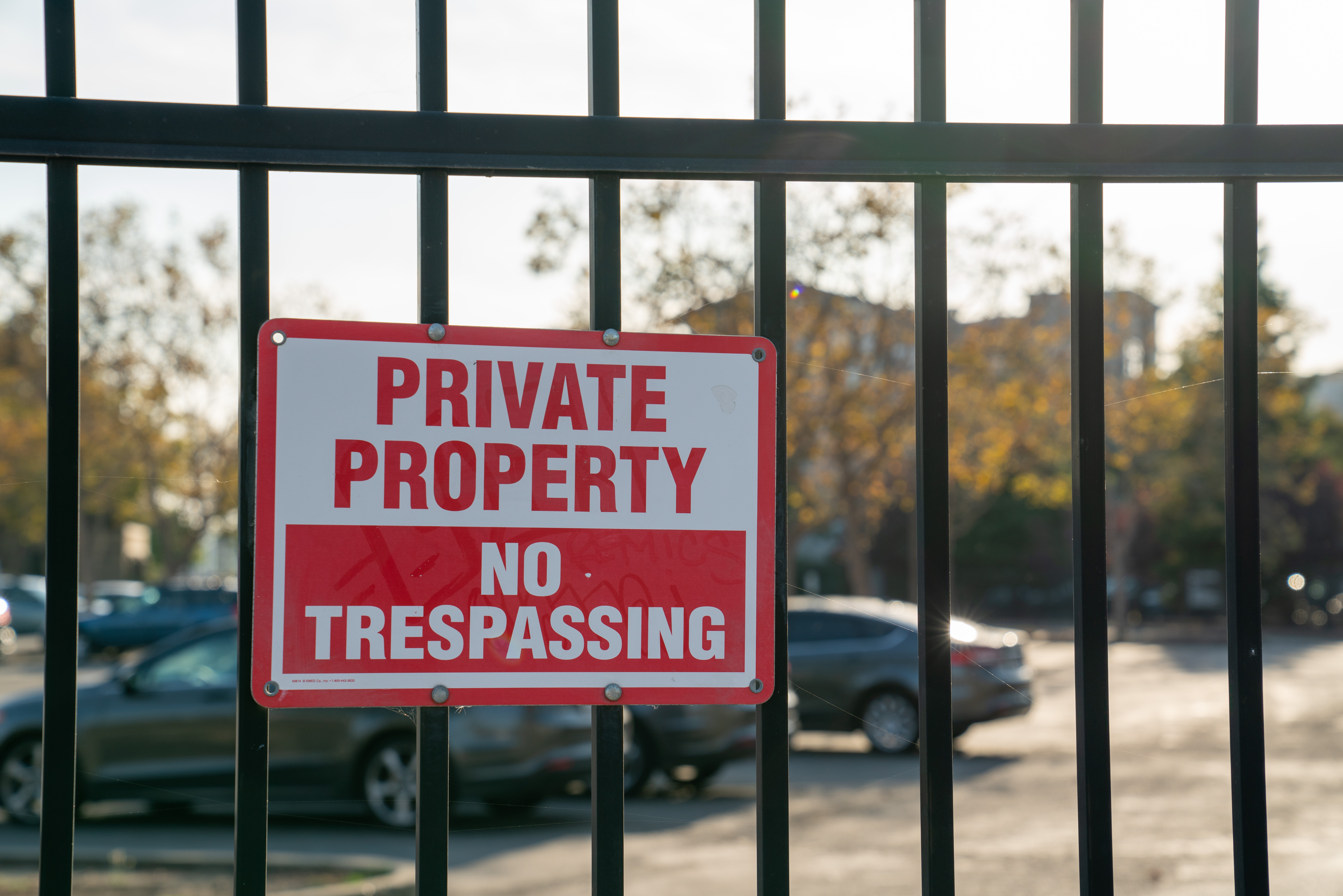 A sign that reads "Private Property / No Trespassing" posted on an apartment complex fence.