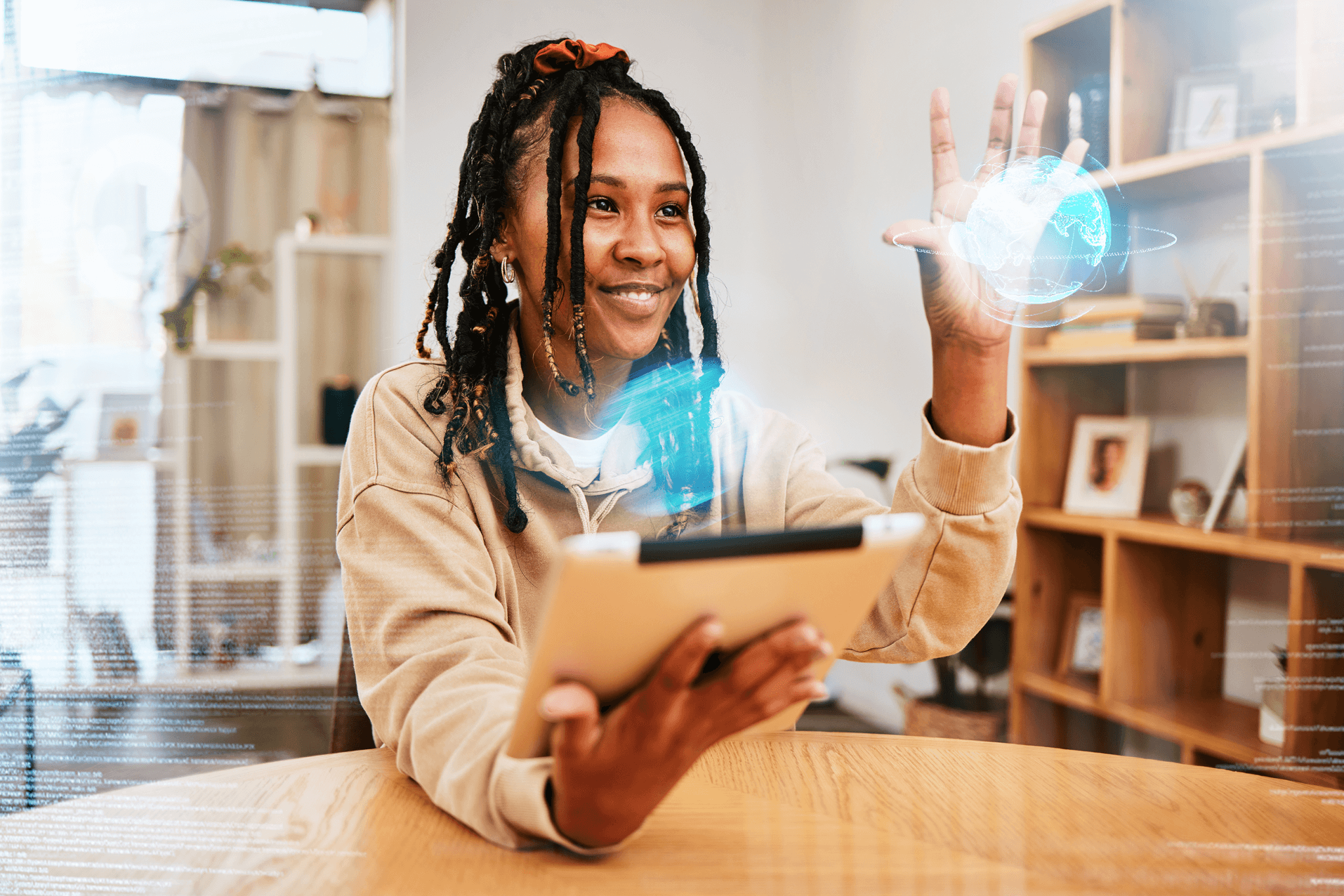 A college student sitting at a table uses a tablet with a holographic globe floating above her hand.